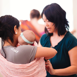 Educator helping caregiver with ring sling